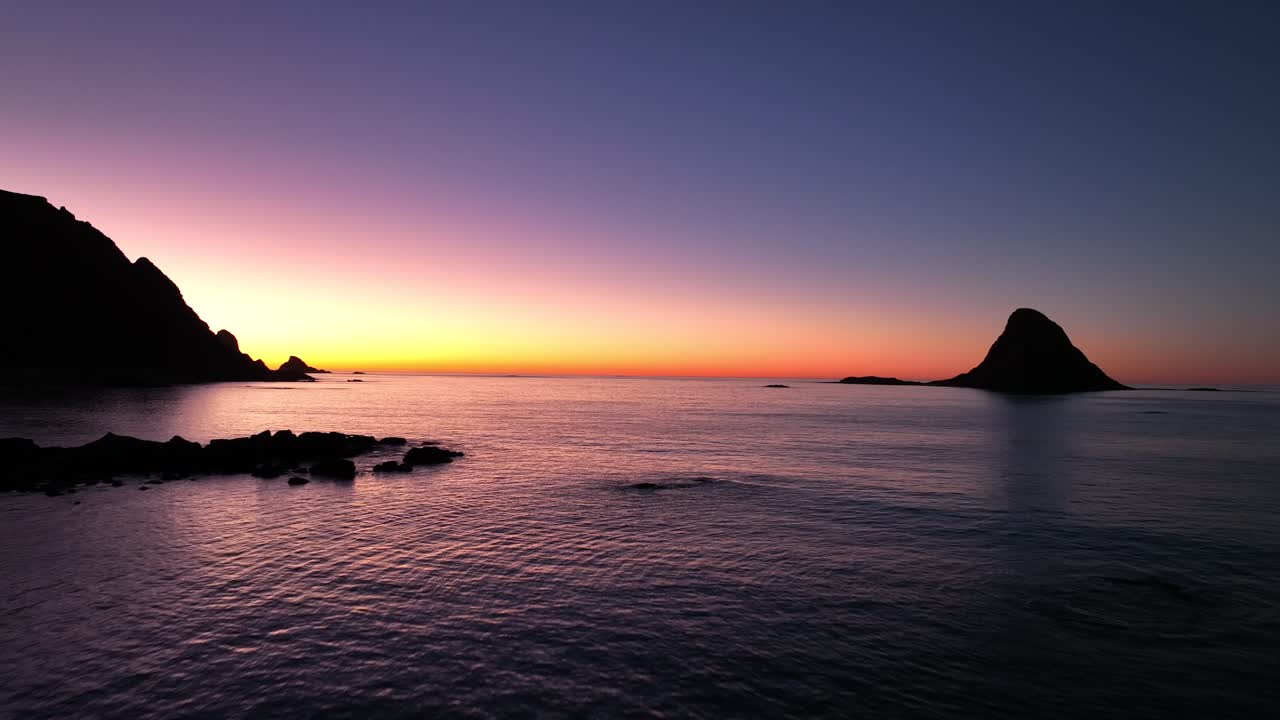Aerial footage of Bleik, Andøya, showcasing steep cliffs, fjords, and the ocean during golden hour. Capturing the serene beauty of Arctic landscapes with vibrant sunset hues.