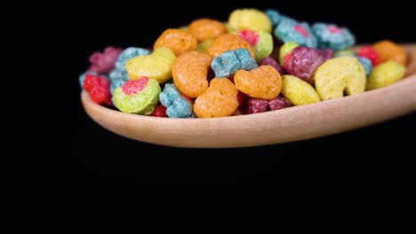 vibrant cereal pieces tumble from a spoon against a black background, captured in slow motion for a dynamic visual effect