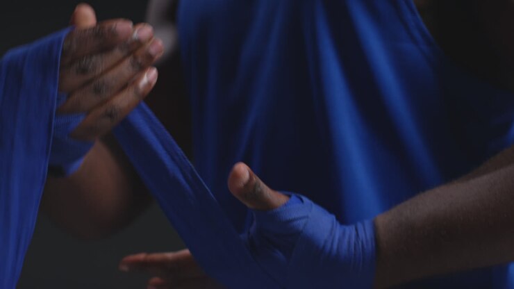 Real Time Close Up Of Male Boxer Wrapping Hands With Protective Bandages Before Boxing Match Or Training Session