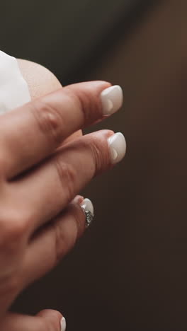 elegant lady in white dress with stylish manicure holds hand on knee sitting in room extreme close view. young woman waiting for queue in salon