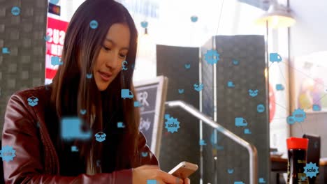 red de iconos digitales contra una mujer asiática que usa un teléfono inteligente en un café
