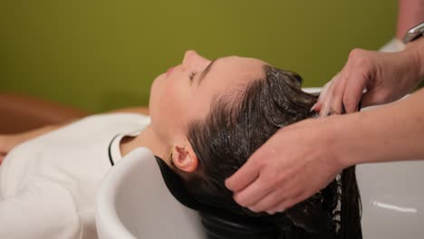 woman relaxing while having hair washed in salon sink. a woman enjoys a professional hair wash in a beauty salon, feeling calm and refreshed during the treatment
