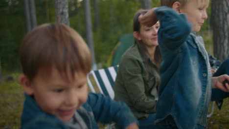 happy little boys are resting at nature with parents throwing stones in water of lake family weekend at summer or early fall in woodland