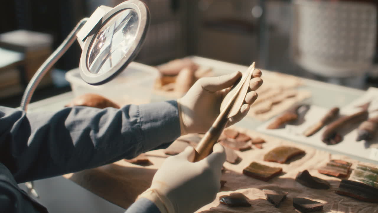 고고학자 의 손 이 대 램프 아래 고대 창끝 을 점검 하고 있다