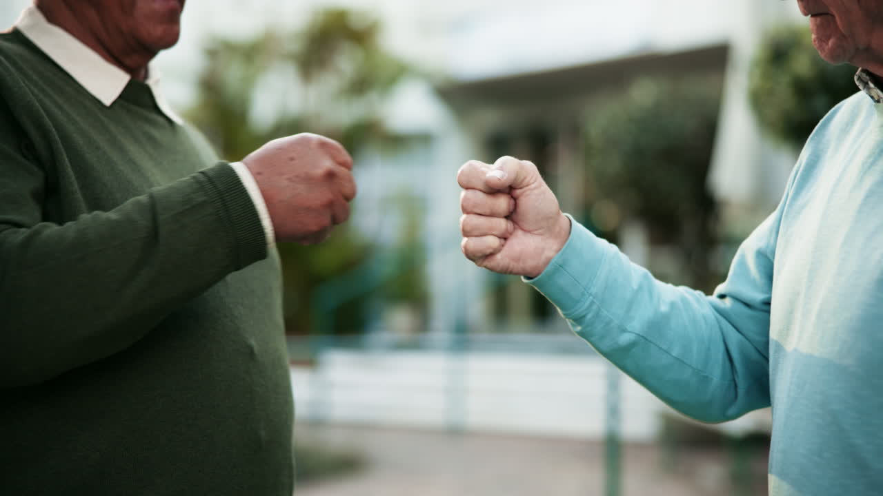 Two senior men fist bumping outdoors