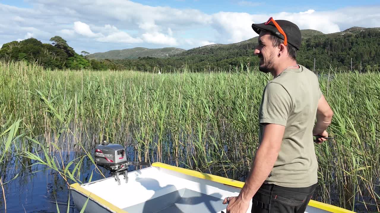 Person Stepping Onto Small Motorboat on a Scenic Lake Shore