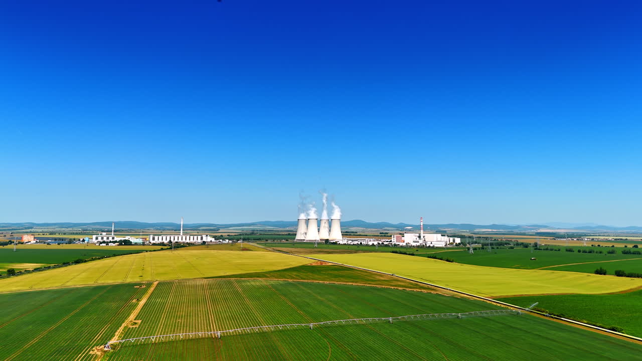 Green agricultural field with irrigation system. Aerial view on the factory working away from the city