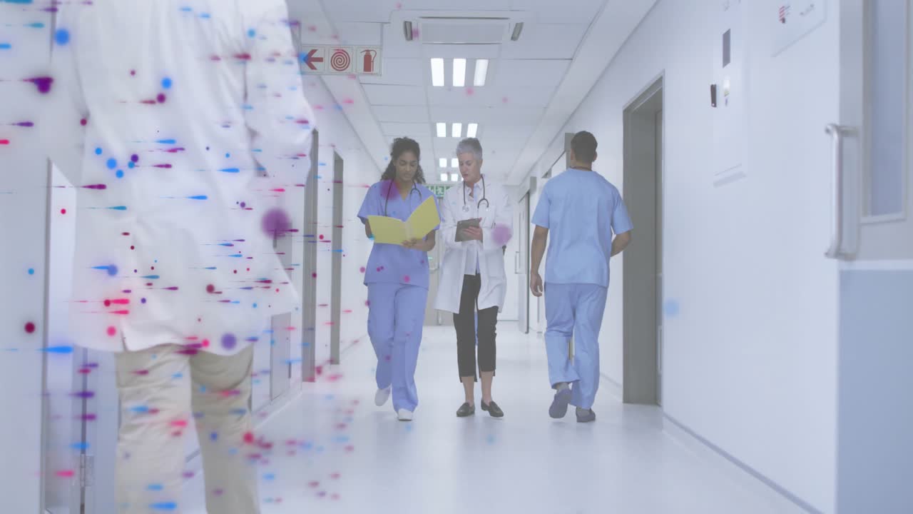 Una enfermera inicia el relevo de información abriendo una carpeta, mientras un médico toca su tableta caminando por un pasillo de hospital.