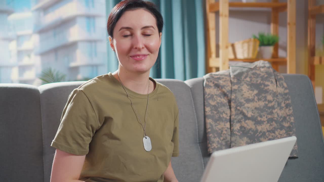 ノートパソコンの前に座り、カメラを見ている若い軍人の女性のポートレート。