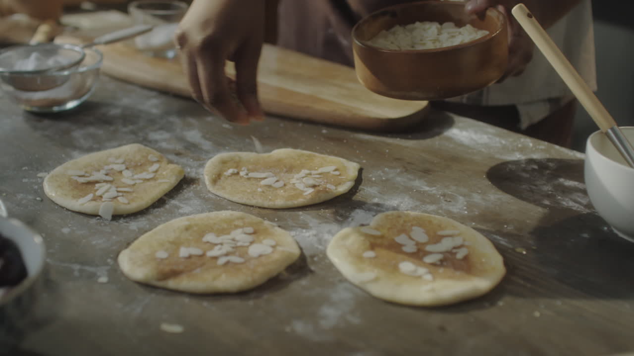 Hands preparing sweet pastries with almond flakes