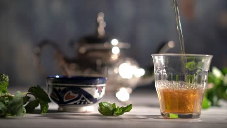 cinemagraph of tea midway pouring into a glass with moroccan tea set and mint