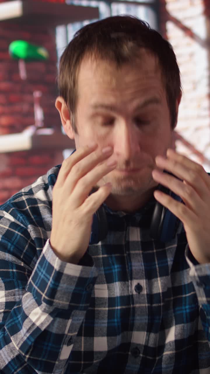 Vertical video Man relaxing in apartment, texting friends on laptop