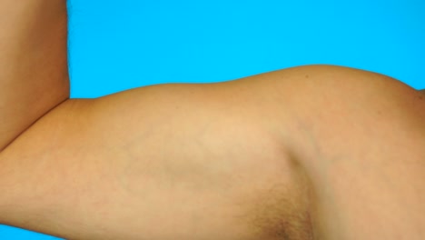 young thin man arm on blue background.