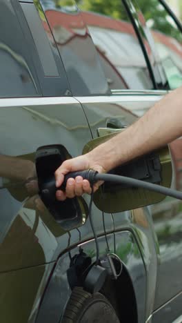 Vertical video Driver leaving electric SUV car plugged into charger while going to work