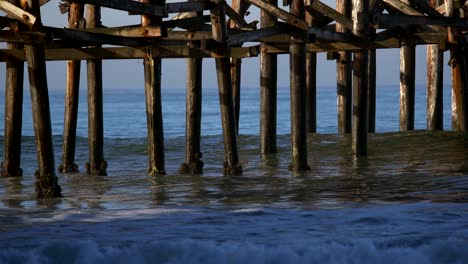 ocean waves hitting the legs of the crystal beach pier, san diego, california