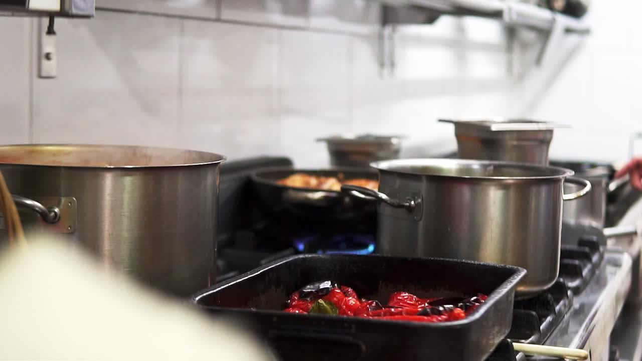 Imagem panorâmica de um chef preparando uma refeição deliciosa e demoradamente elaborada na placa vitrocerâmica com panelas.