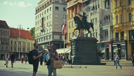 tourists in josip jelačić square, zagreb, standing near the equestrian statue of ban jelačić.