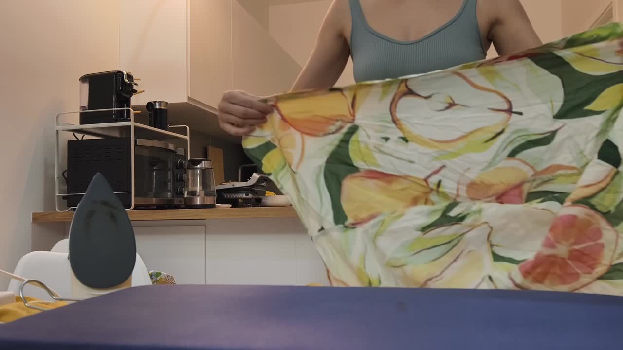Mulher passando roupas em casa