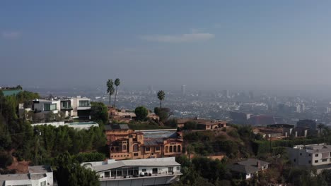 Aerial-shot-flying-over-hill-to-reveal-Los-Angeles-with-hazy-and-smoky-air