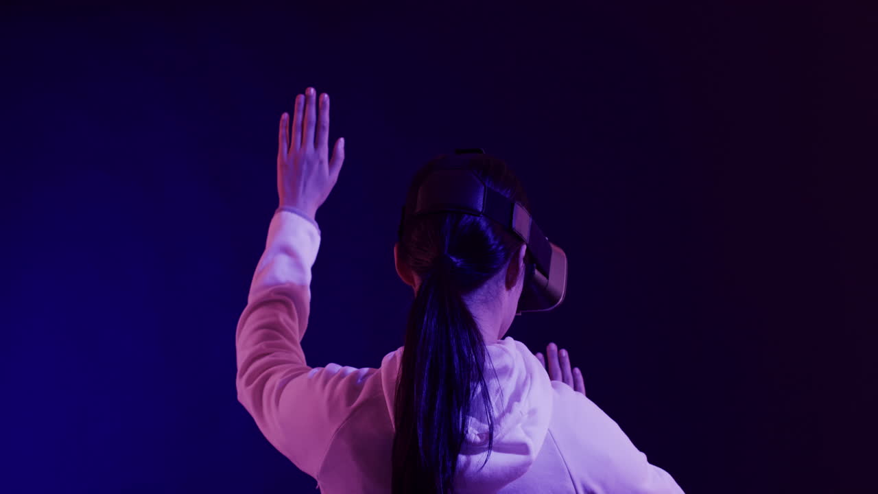 mujer asiática usando auriculares vr, tocando pantalla virtual en fondo azul, cámara lenta