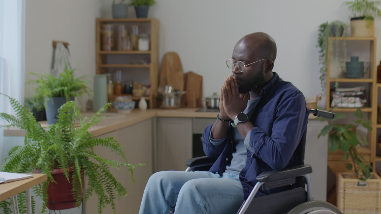 Black Man in Wheelchair Praying at Home