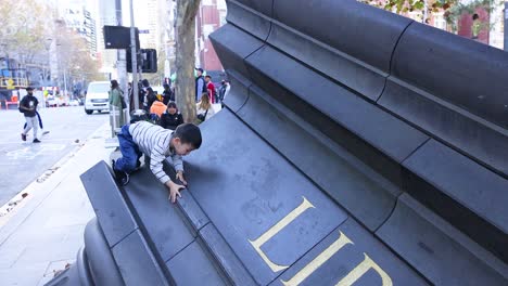 boy climbing large outdoor library sculpture