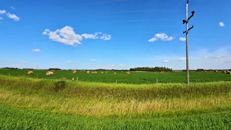 4 km de longitud lenta de un camino trasero con postes hidráulicos que pasan por campos de cultivo llenos de balas de heno