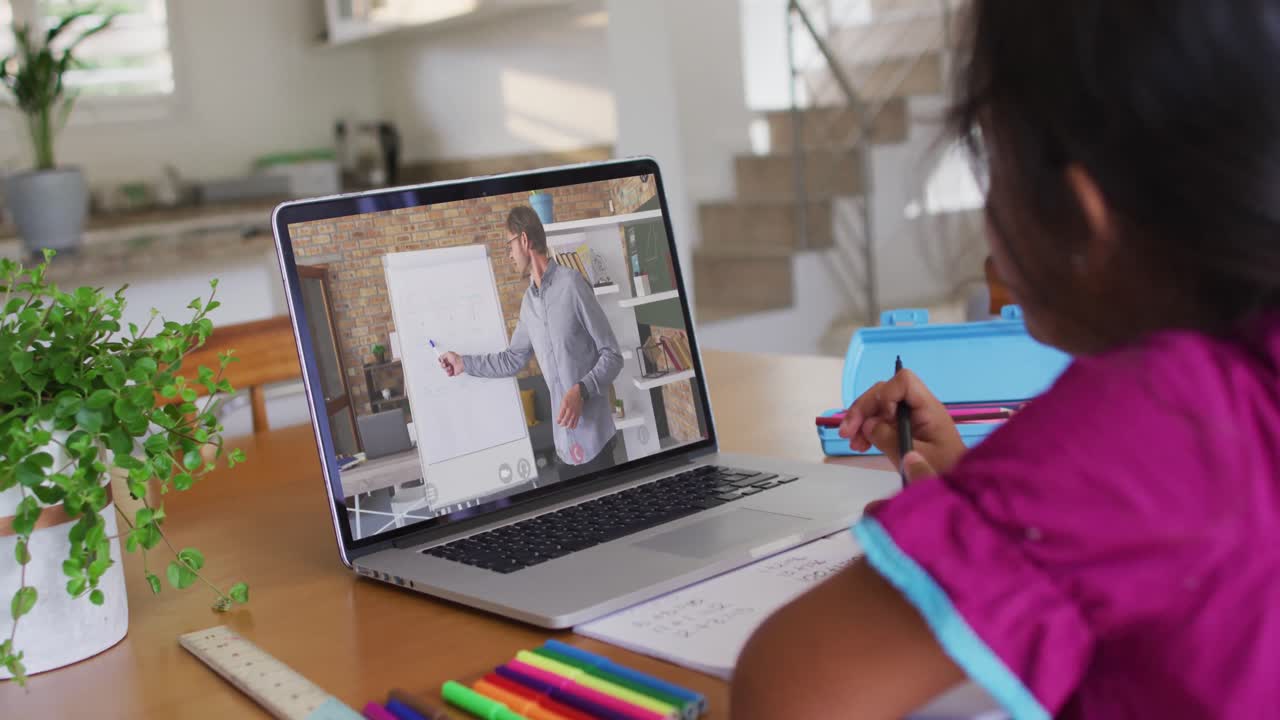 chica de raza mixta sentada en un escritorio usando una computadora portátil teniendo una lección escolar en línea