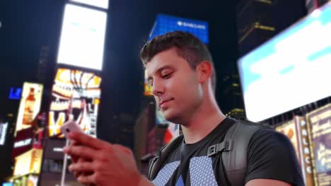 man using phone in times square at night