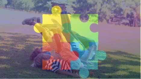Animation-of-jigsaw-puzzle-over-diverse-children-lying-on-green-filed-and-raising-legs-towards-head