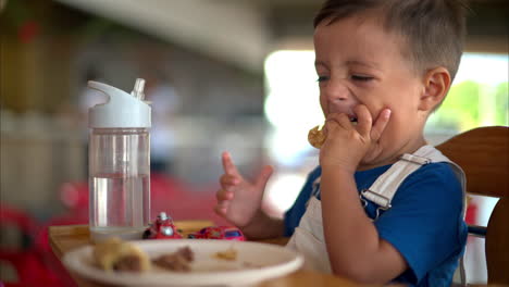 slow motion close up of a young latin toddler eating a barbacoa taco with his hands in a mexican restaurant