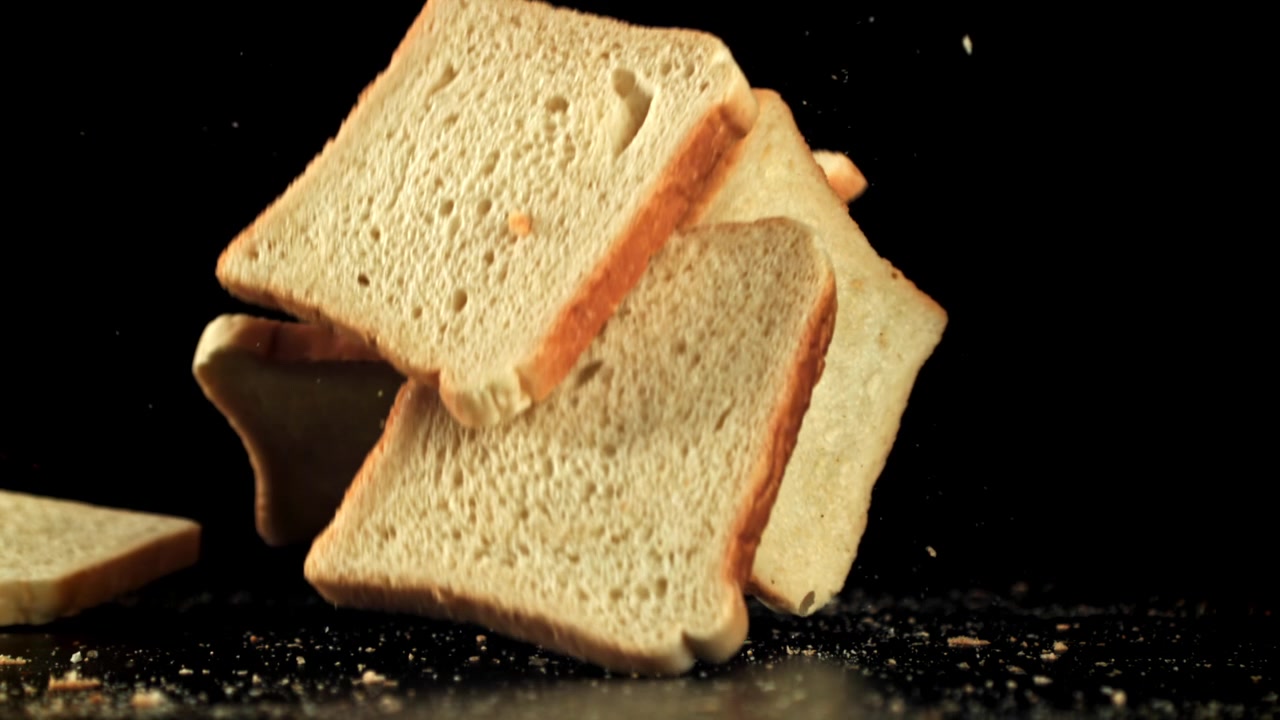 Fresh Sliced Bread Falling in Slow Motion with Crumbs on Black