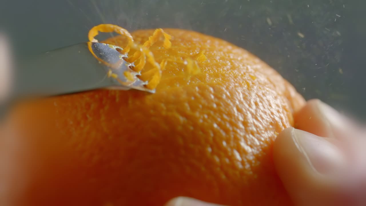 A Tool Crosses Along the Outside of an Orange to Peel the Zest