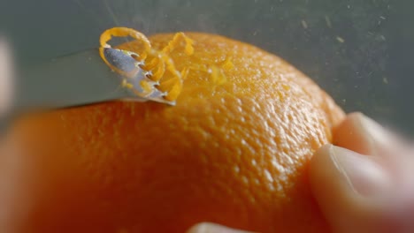 a tool crosses along the outside of an orange to peel the zest