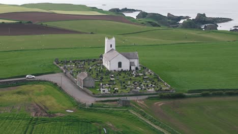 Aerial-Retreating-Pan-Up-Shot-of-Coastal-Church-with-Sheep-in-Northern-Ireland