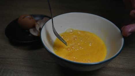 righthand scrambling eggs in a bowl for breakfast