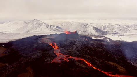 Las-Tomas-Cinematográficas-Aéreas-Tomadas-Por-Un-Dron-De-4k-Capturan-La-Belleza-única-De-Un-Volcán-Y-La-Lava-En-Cascada,-Con-El-Telón-De-Fondo-Escénico-De-La-Majestuosa-Cordillera-De-Los-Alpes.