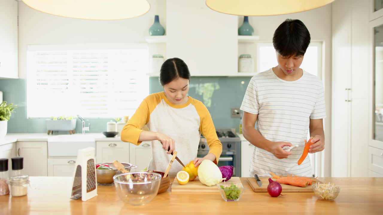 Preparing vegetables in kitchen, Asian brother and sister cooking healthy meal together