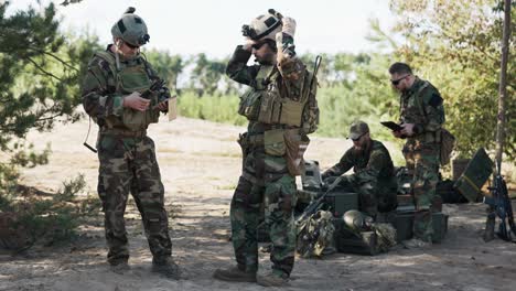 a group of soldiers is getting ready to go on a patrol in the field, they set up a strategy, a location, they follow a map on a computer, a tablet, a troop leader puts on a helmet