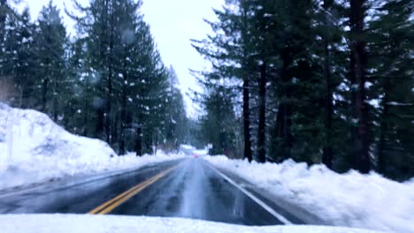 Dramatische-Zeitrafferaufnahme-Eines-Autos,-Das-Durch-Schnee,-Verschneite-Berge-Und-Kiefern-Im-Winter-Fährt.-Auf-Den-Angrenzenden-Fahrspuren-Sind-Andere-Fahrzeuge-Zu-Sehen