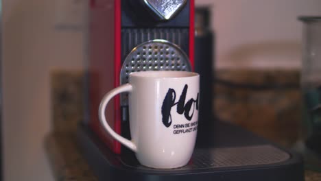 an extreme close up of espresso dripping out of a machine into a mug