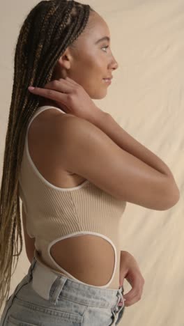 studio portrait shot of young woman with long braided hair against neutral background 1