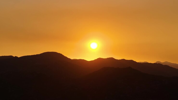 Sol laranja brilhante desce sobre colinas escuras em camadas perto do mirante de Kotor, criando uma paisagem calma de crepúsculo em silhueta