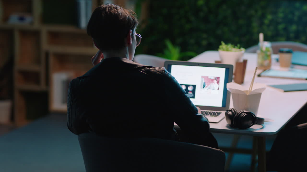 노트북 컴퓨터를 사용하여 늦게 일하는 젊은 백인 사업가 회사 프로젝트에 대한 창의적인 아이디어를 계획하는 밤에 사무실에서 헌신적인 기업가