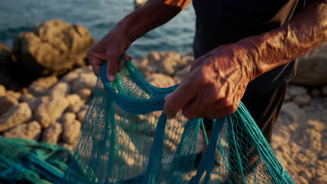 old fisherman tending to his net at sunset