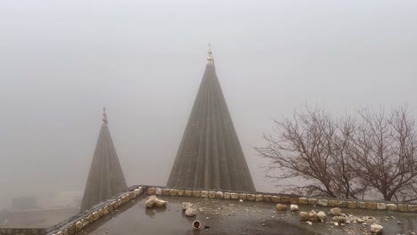 misty, foggy, rainy day in lalish, kurdistan iraq overlooking the yazidi temple spires