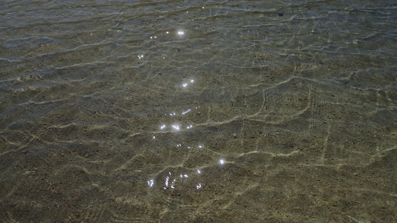 Water ripples over the shallow end of a clear glacial lake in the Sierra Nevada mountain range