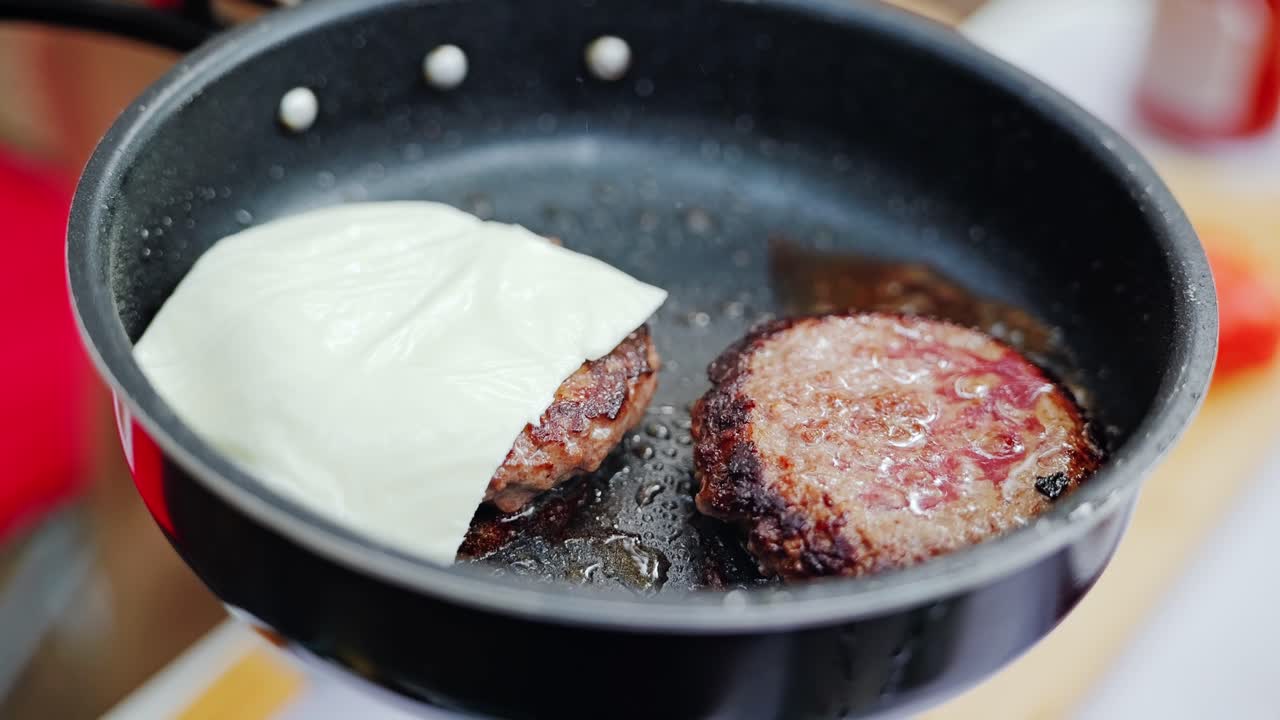 Close-up moment of cheese slice placed on burger patty over sizzling heat