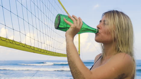 mujer joven bebiendo en la playa.