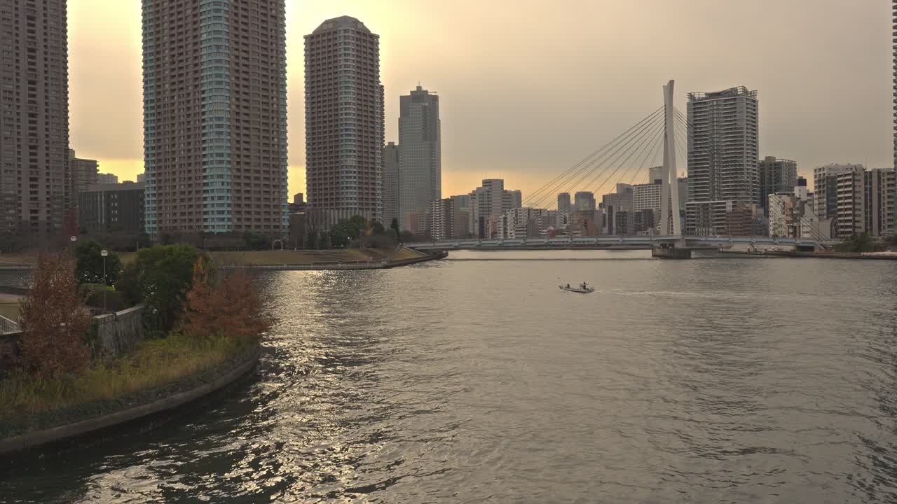 The Eitai Bridge gracefully spans the Sumida River in Tokyo, Japan, with modern buildings lining the riverbanks.